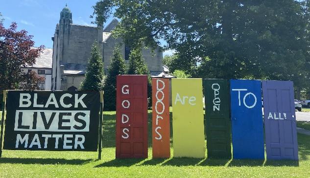 Picture of Black Lives Matter sign next to different colored doors that say, God's doors are open to all.