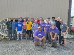 Group of people posing in purple shirts