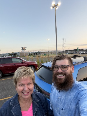 Two people smiling for a selfie outside a prison facility