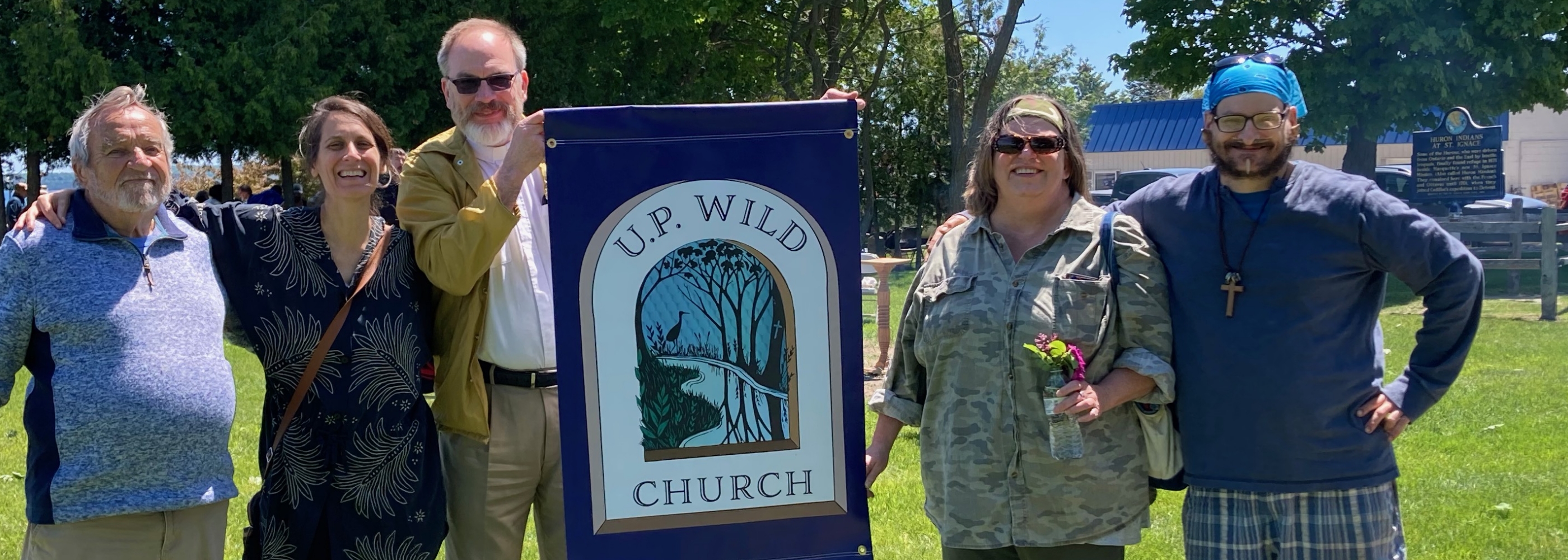 Group of people holding up an Up Wild Church banner